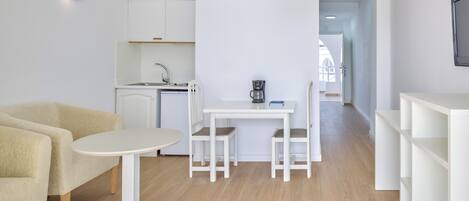 A modern, minimalist living space with a kitchen, dining area, and seating.