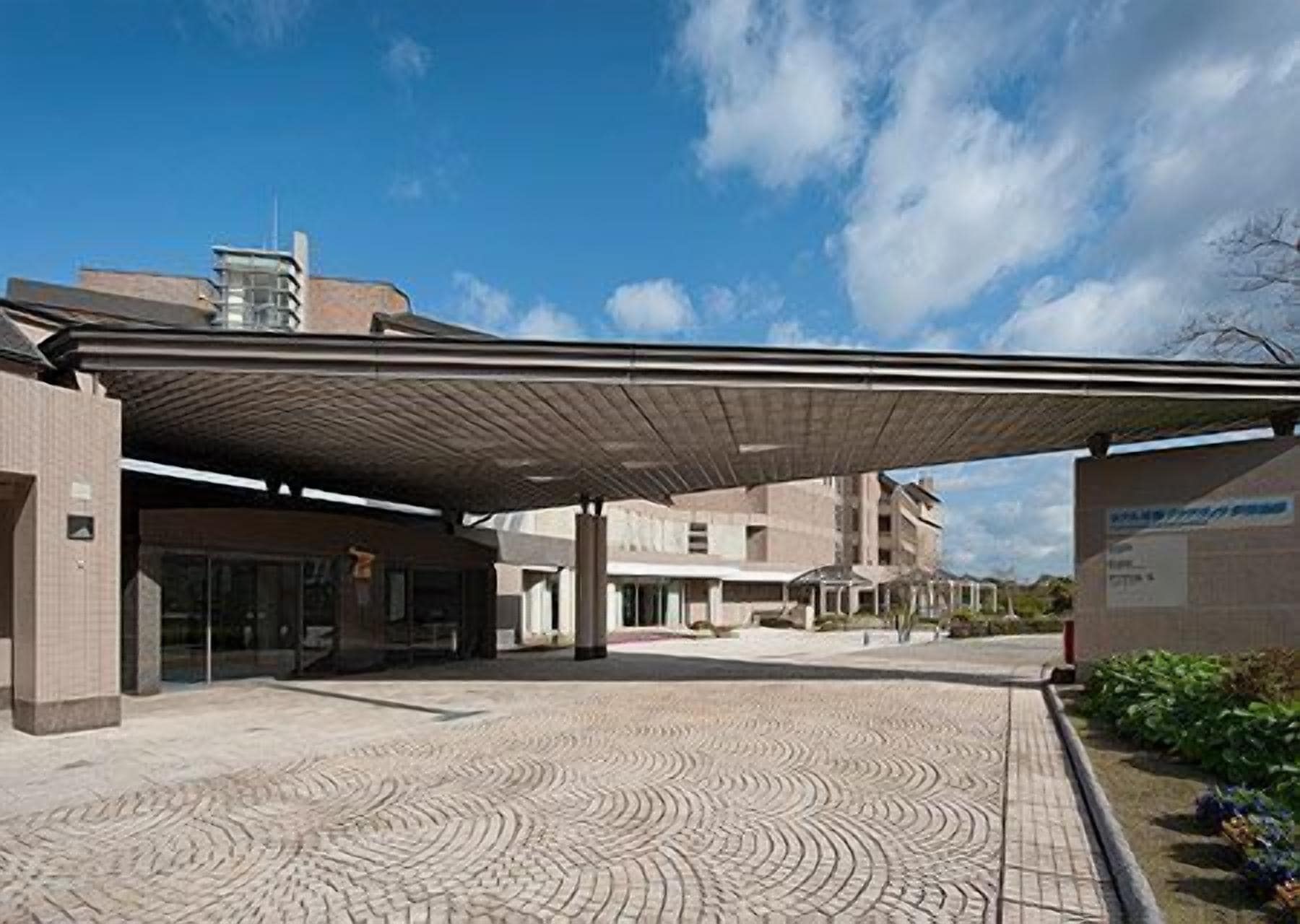 A covered entrance to a building with a patterned pavement and a clear sky.