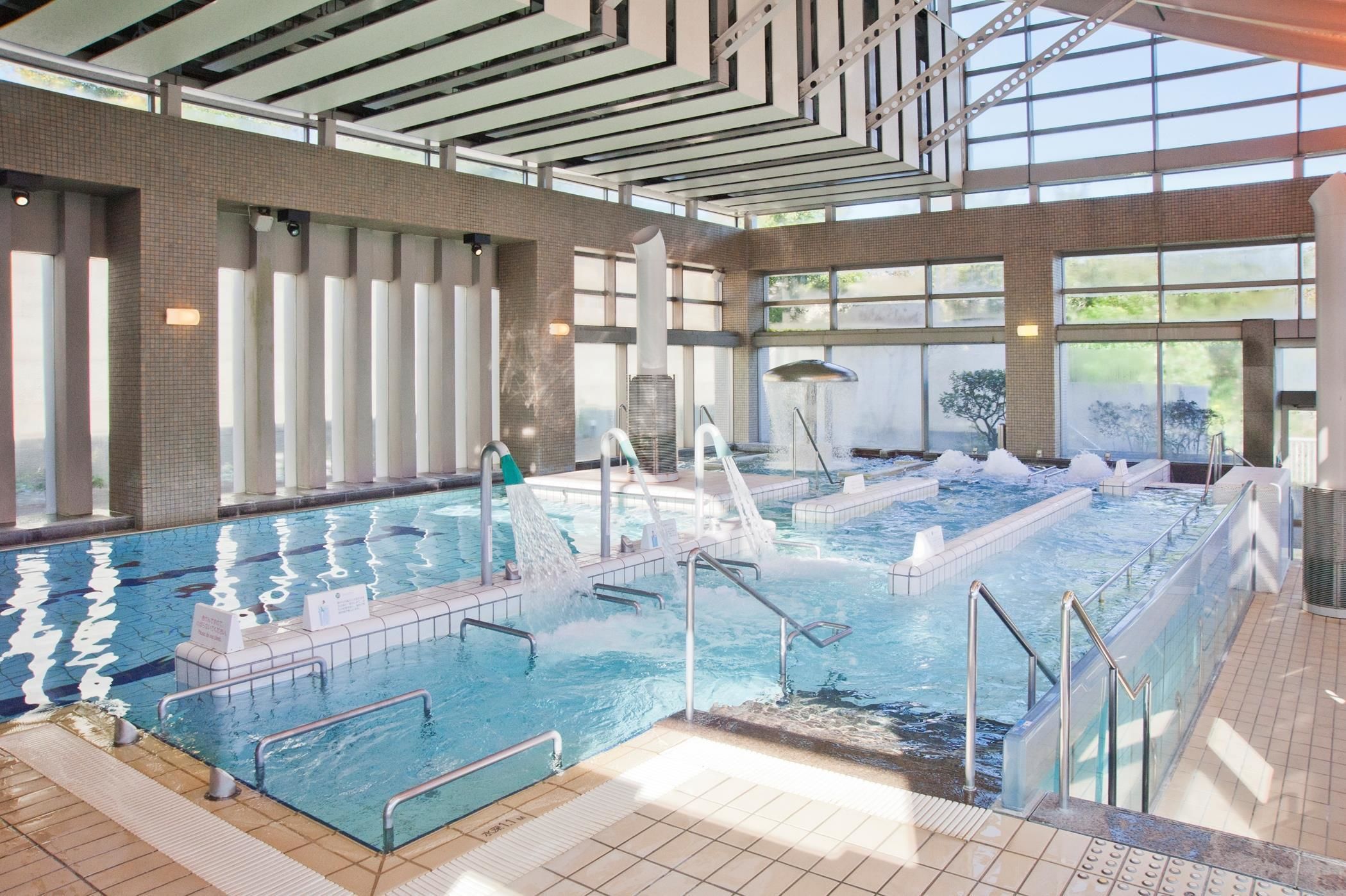 An indoor swimming pool with multiple lanes, a water slide, and a sauna area.