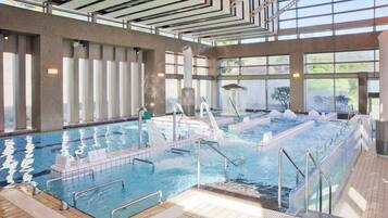 An indoor swimming pool with multiple lanes, a water slide, and a sauna area.