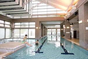 Una piscina interior con carriles delimitados, suelo de baldosas y un techo alto con tragaluces.