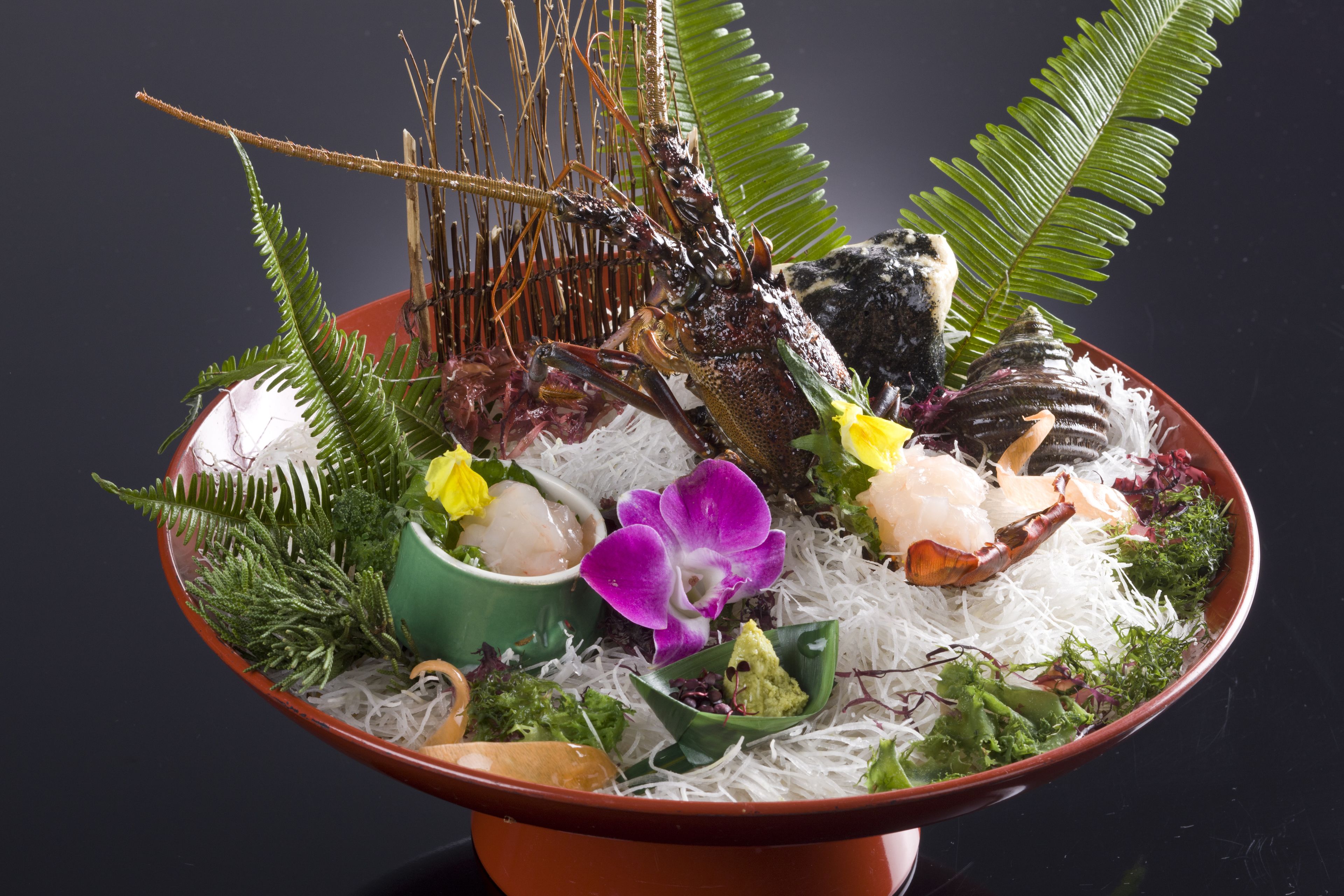 Un cuenco de mariscos con diferentes guarniciones y una planta decorativa.
