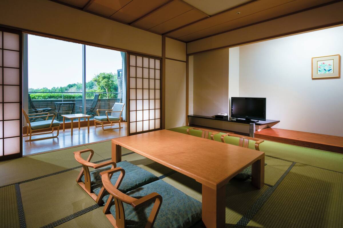 Une pièce de style japonais traditionnel, avec un sol recouvert de tatamis, une table basse et un téléviseur.