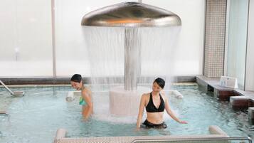 An indoor swimming pool with a central water feature and tiled walls.
