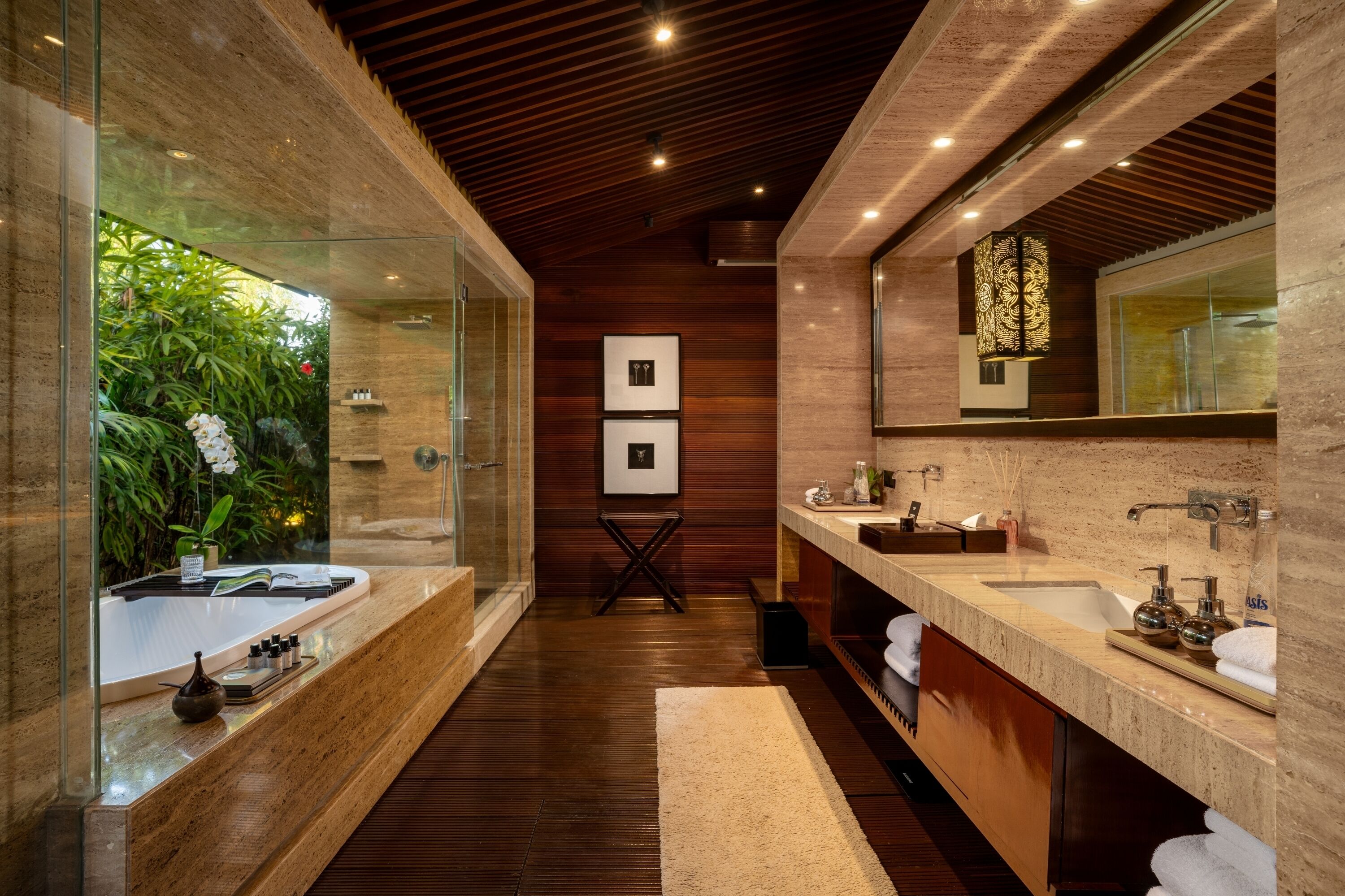 A modern bathroom with a glass enclosure, wooden flooring, dual sinks, and a large mirror.
