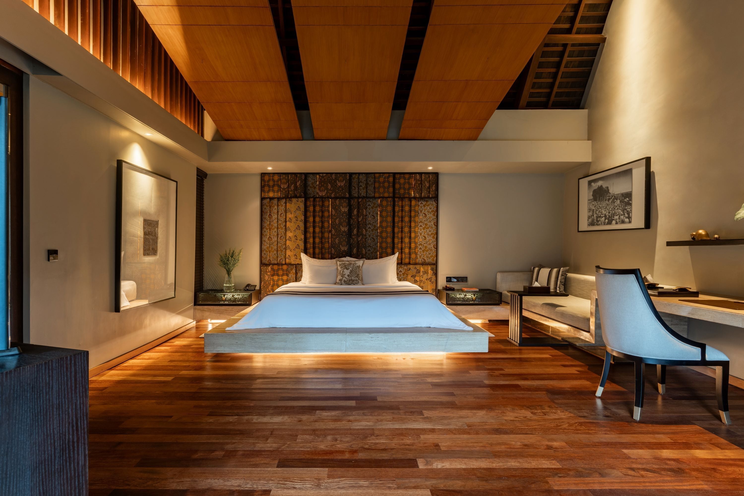 A modern bedroom with a large bed, a desk, and a chair.