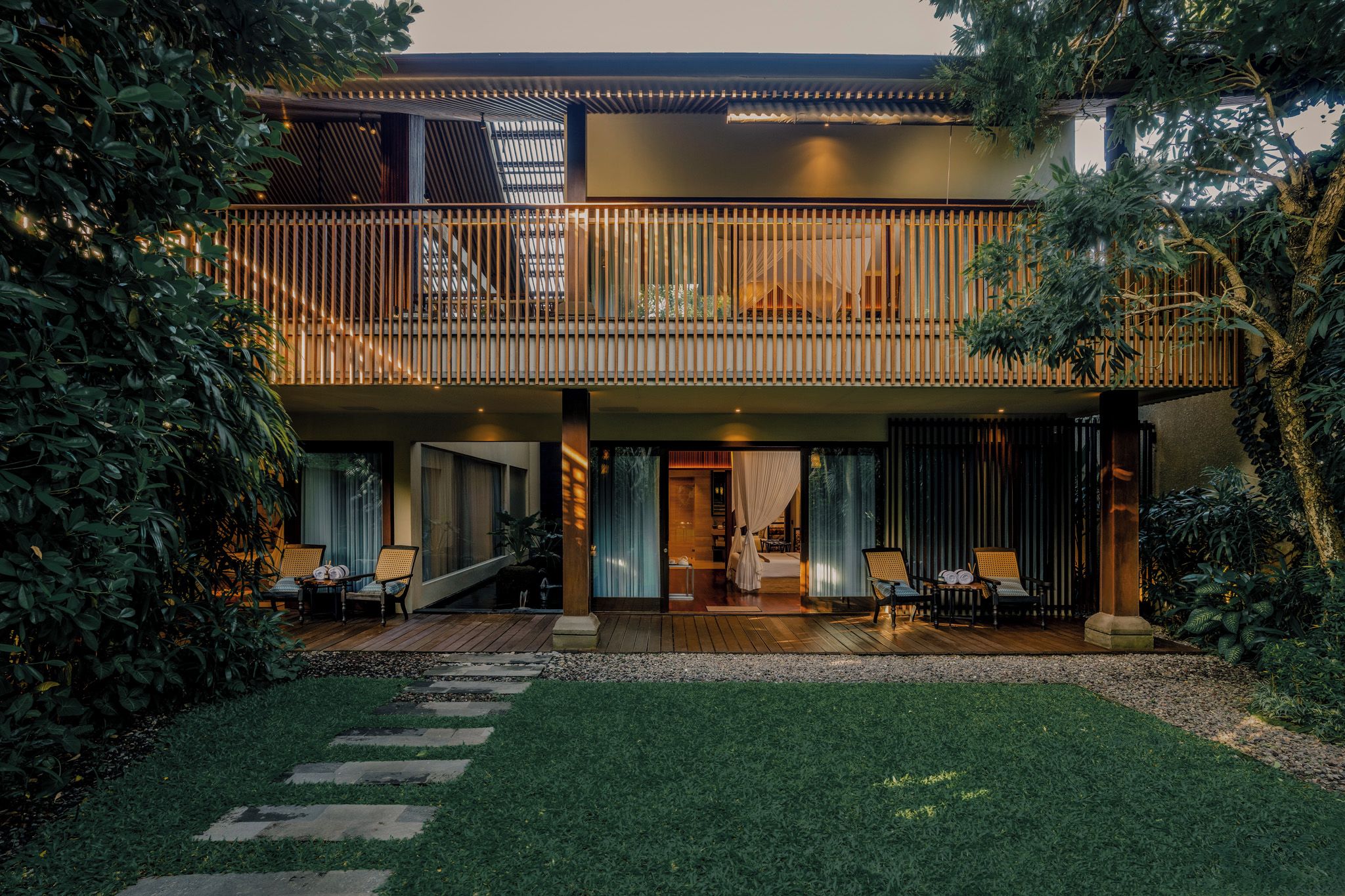 Een tweelaags huis met een balkon, terras en tuin.
