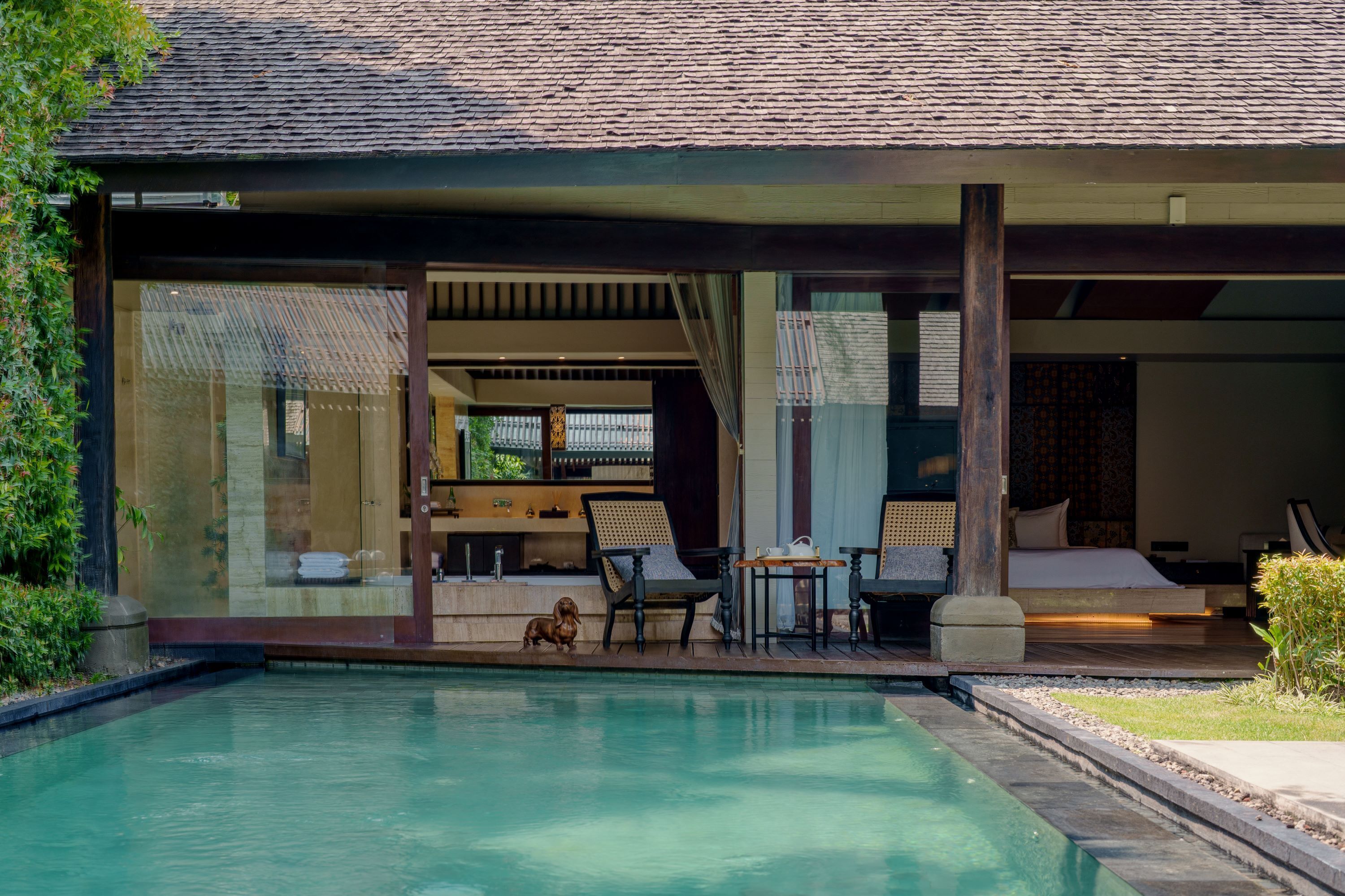 A modern villa with a swimming pool, outdoor seating, and a view of the surrounding landscape.