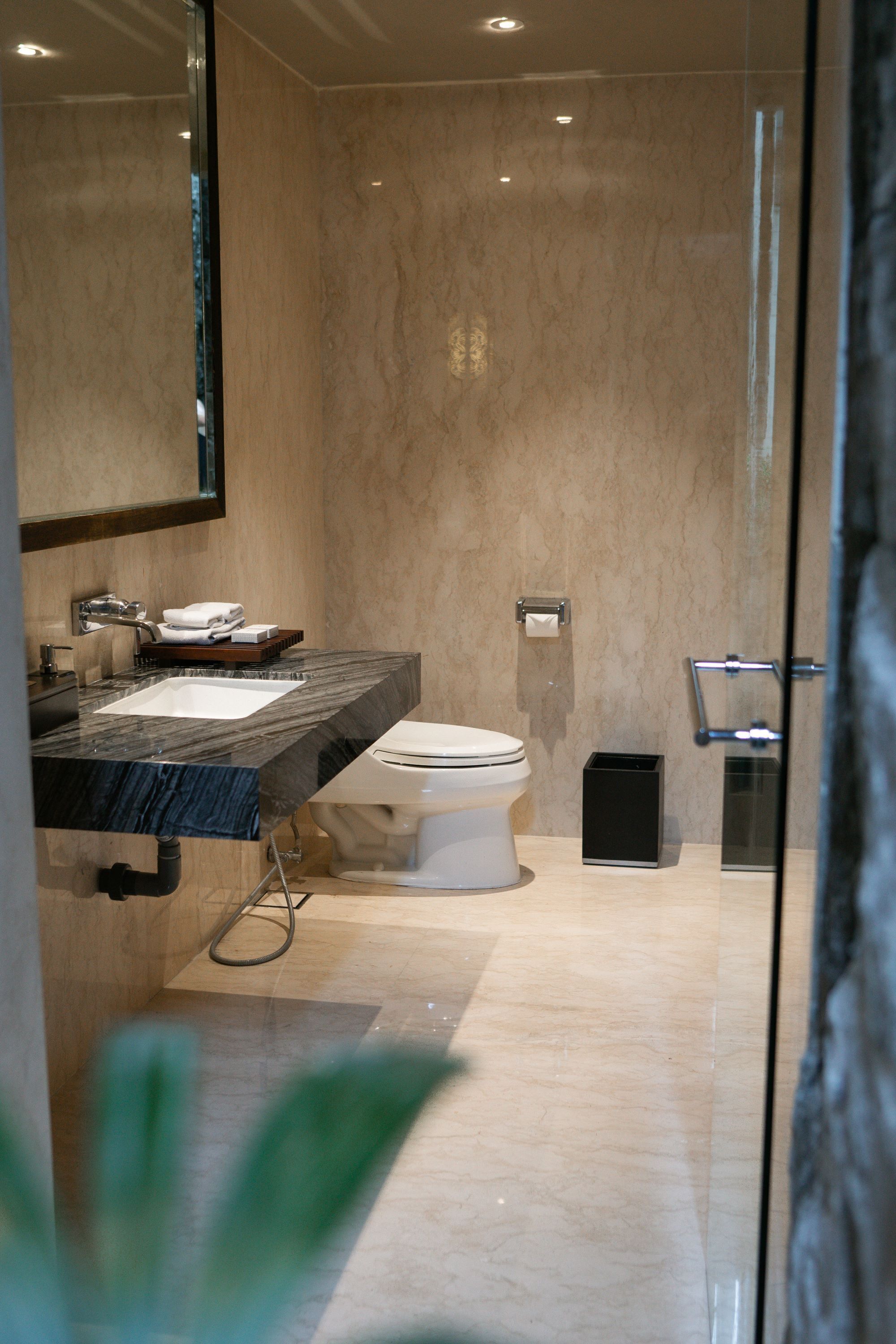 A modern bathroom with a marble sink, a toilet, and a glass shower enclosure.