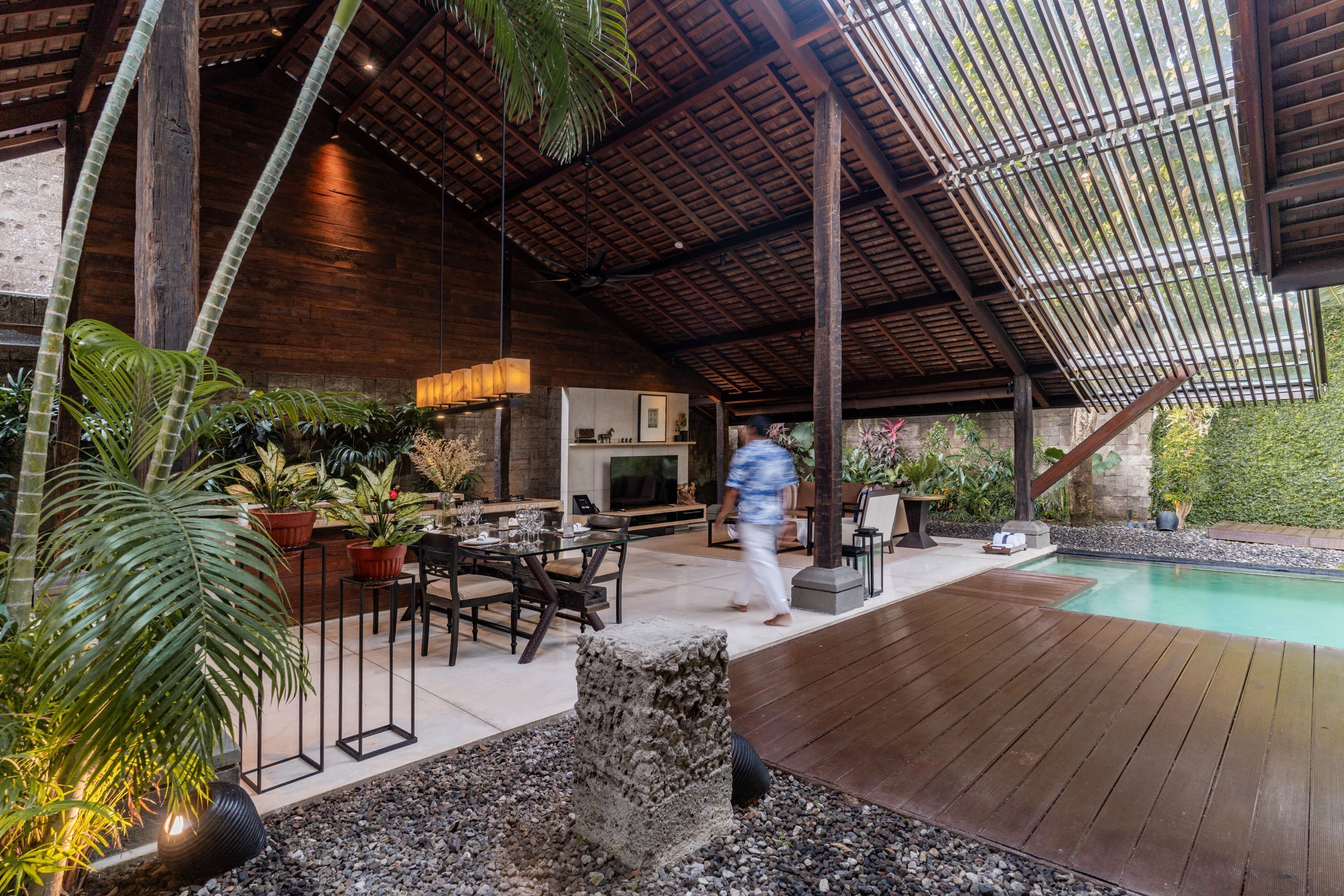 An outdoor patio area with a pool, wooden deck, and potted plants.