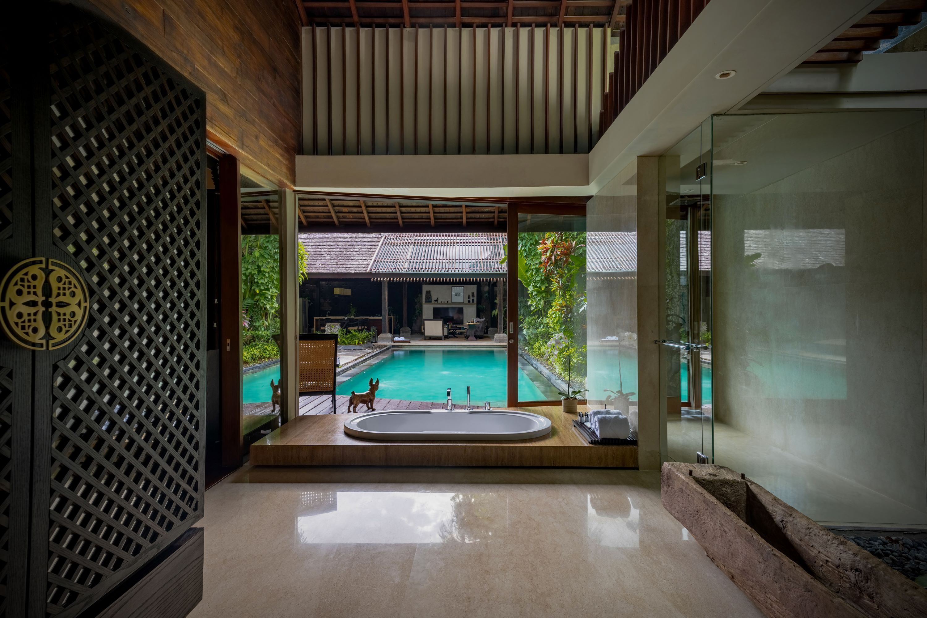Ein modernes Badezimmer mit einer großzügigen Badewanne, einer Duschkabine aus Glas und Blick auf Pool und Außenbereich.