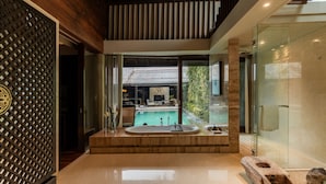 A modern bathroom with a glass shower, a sink, and a view of a pool and outdoor area.