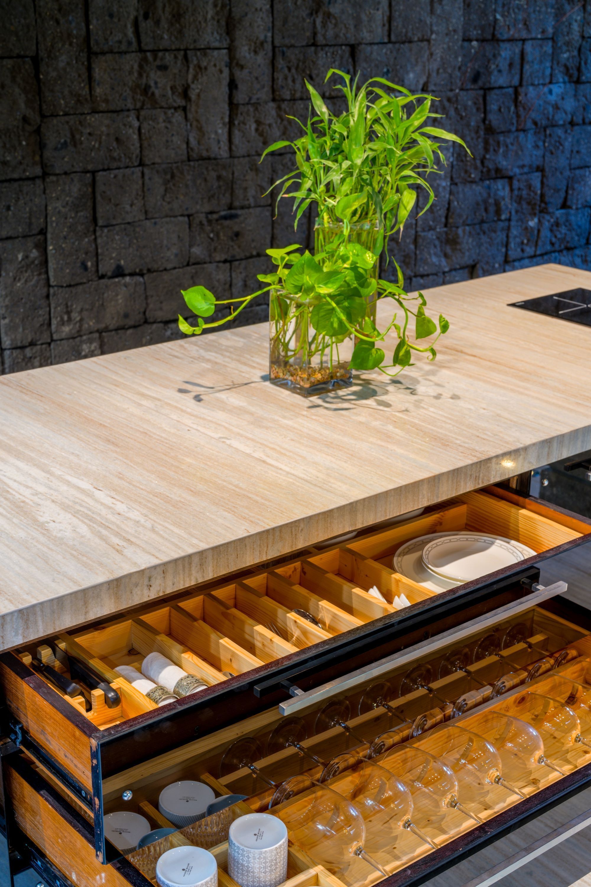 A kitchen with a wooden countertop, a potted plant, and a wine rack with glasses.