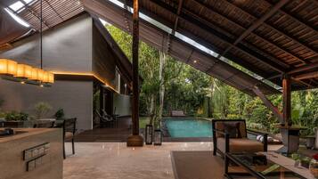 A modern outdoor living area with a pool, seating, and a wooden structure.