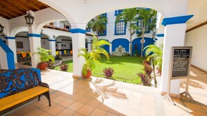 A courtyard with a bench, potted plants, and a signboard. - Azul Sirena (Santa María Huatulco)
