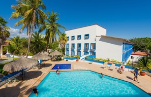 A resort with a swimming pool, palm trees, and a white building with blue accents. - Azul Sirena (Santa María Huatulco)