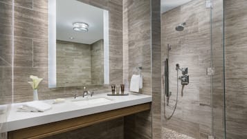 A modern bathroom with a large mirror, a sink, and a glass-enclosed shower.