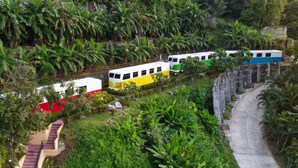 A model train set in a lush garden with a curved pathway and a small bridge. - Memory Karon Resort (Karon)
