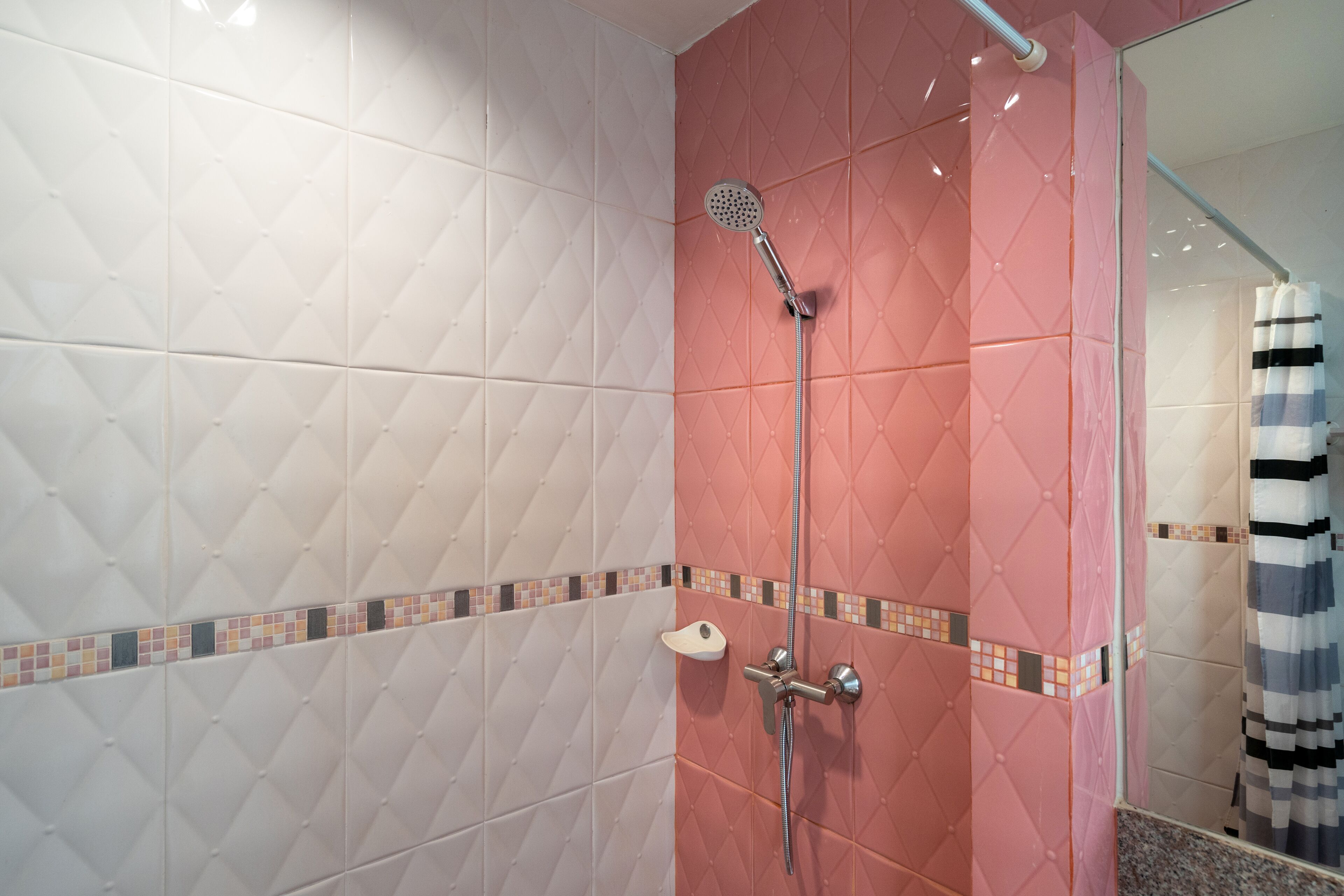 A bathroom with a shower, tiled walls, and a striped shower curtain.