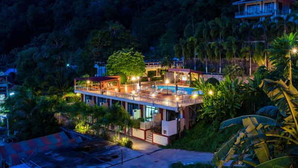 A multi-story hotel with a swimming pool, surrounded by lush greenery and palm trees. - Memory Karon Resort (Karon)