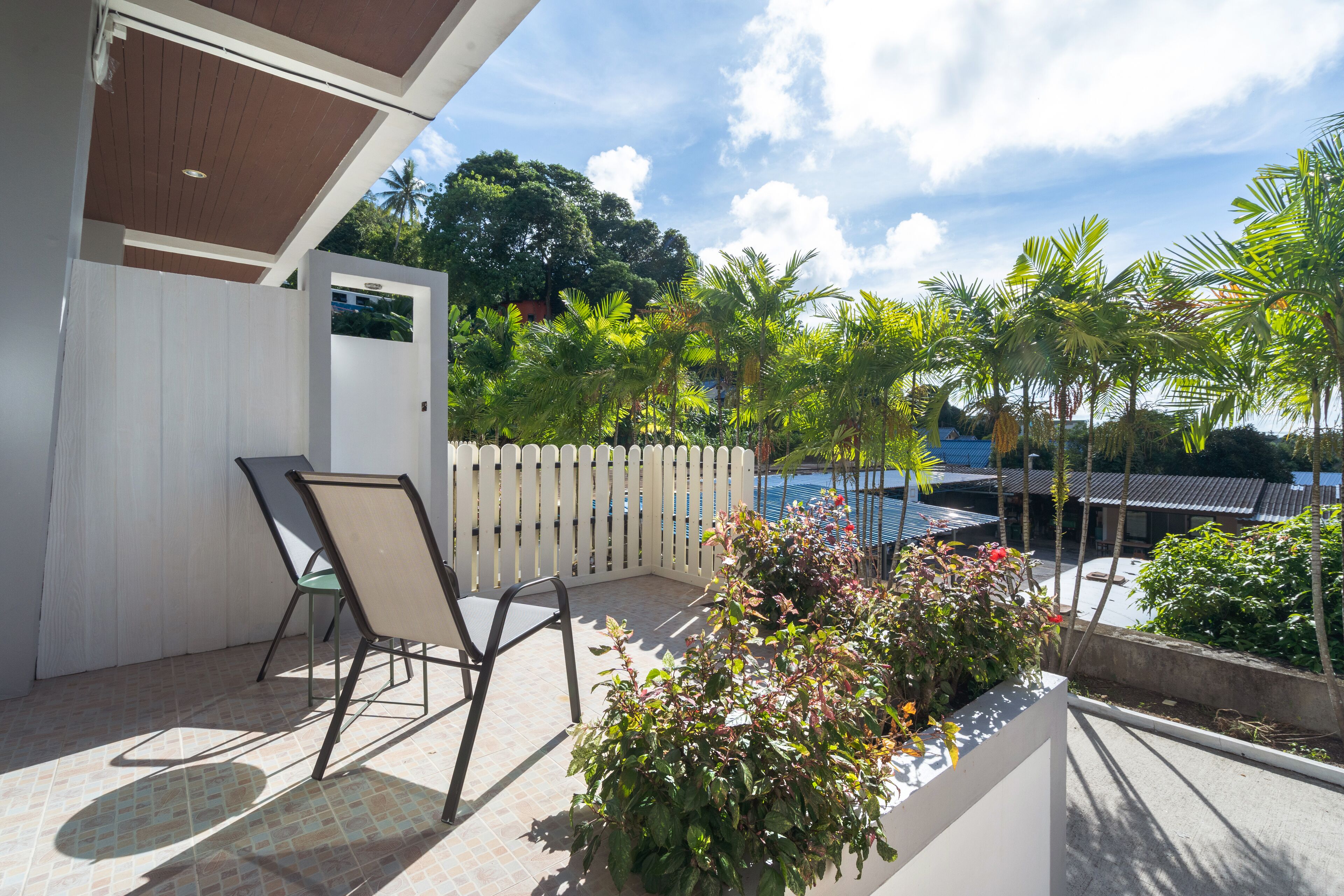 A balcony with a white fence, a pool, and various plants.