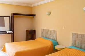 Ein Hotelzimmer mit zwei Betten, einem kleinen Tisch, einem Spiegel und einer Wandleuchte.