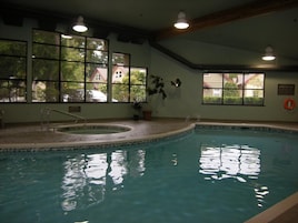 An indoor swimming pool with clear windows, a lifebuoy, and a sign on the wall.
