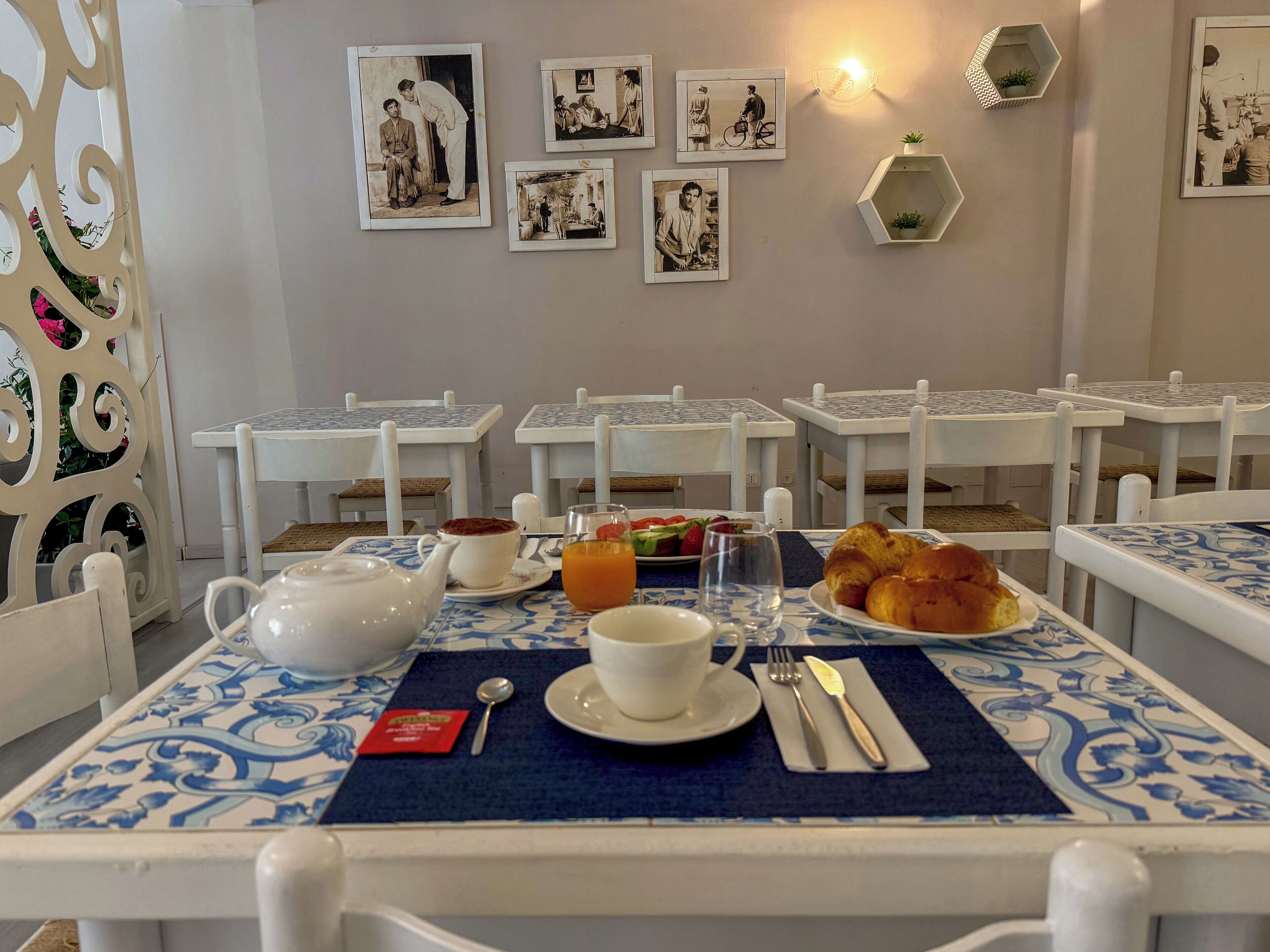 A dining area with tables set for breakfast, including croissants and fruit.