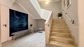 Un intérieur moderne avec un escalier, un grand tableau et un coin salon.