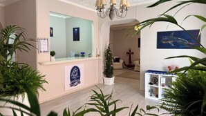 Un hall d’accueil d’hôtel avec un comptoir, un lustre et divers éléments décoratifs sur les murs, notamment une grande ancre et un navire.