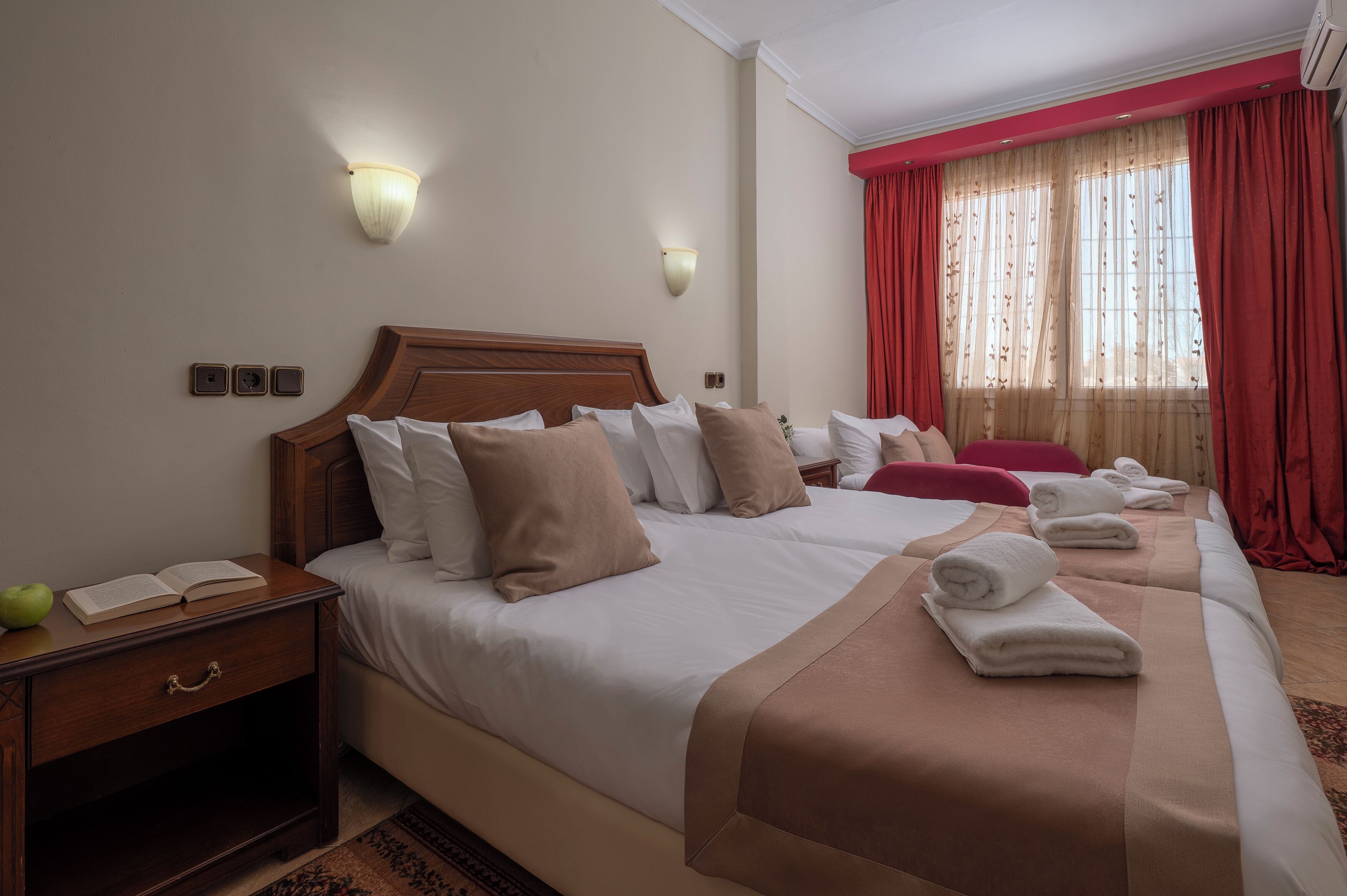 A hotel room with a large bed, bedside tables, a nightstand, and a window with curtains.