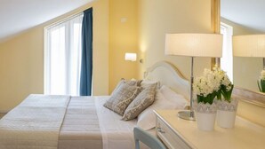 A hotel room with a bed, bedside table, lamp, and flowers.