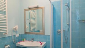 A bathroom with a sink, mirror, and shower.
