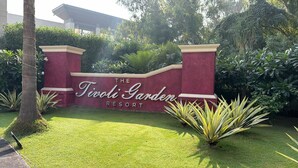 A sign for The Tivoli Garden Resort with a well-maintained lawn and tropical plants. - Tivoli Garden Resort (New Delhi)