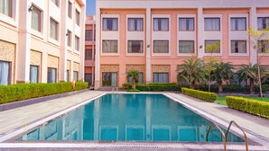 A swimming pool surrounded by a building with multiple floors and balconies. - Tivoli Garden Resort (New Delhi)