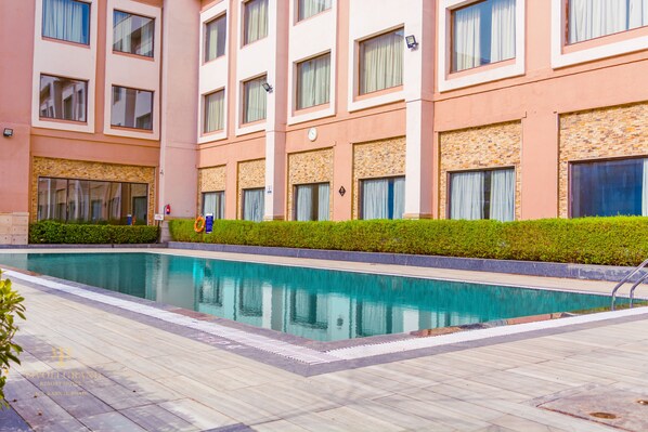 Un hotel con piscina, varias ventanas y fachada de ladrillo.