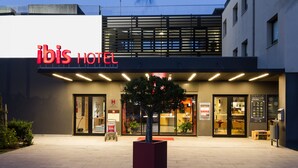 The exterior of the ibis Hotel with a modern facade, large glass windows, and a prominent red sign. - ibis Lisboa Sintra (Sintra)