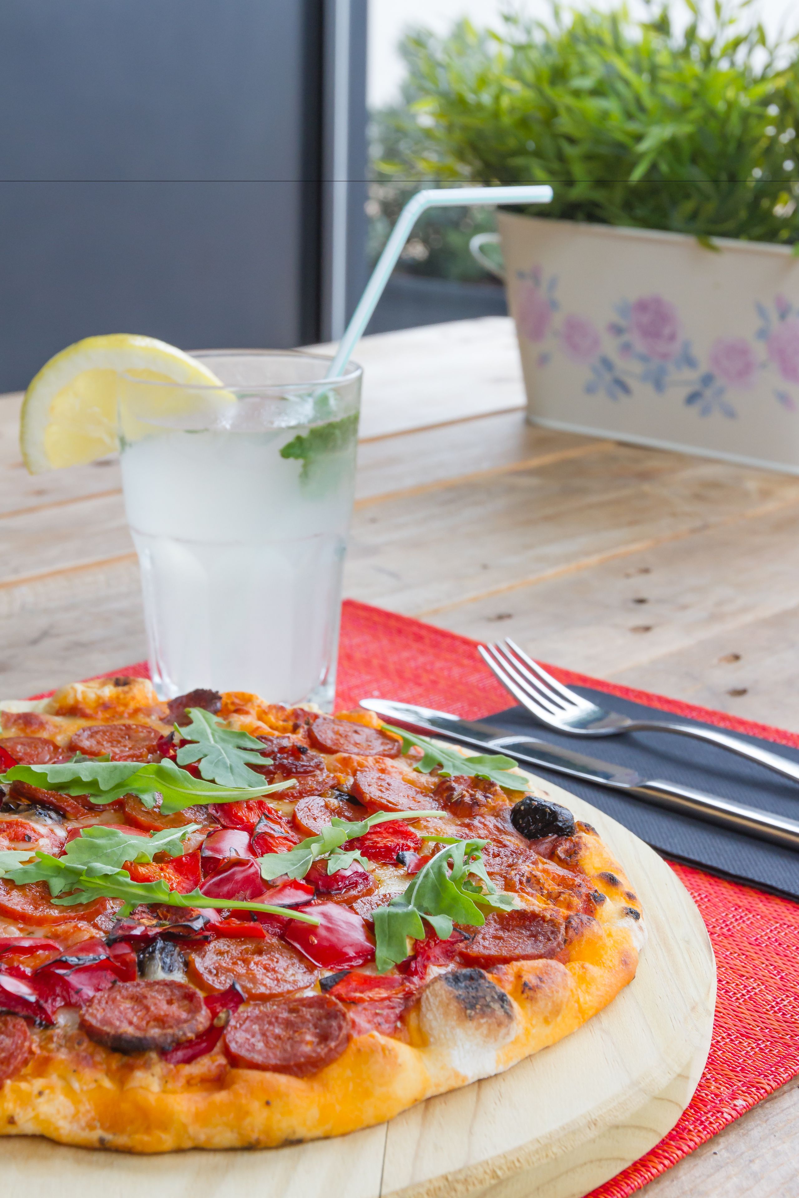 A pizza with toppings and a glass of water on a wooden table.