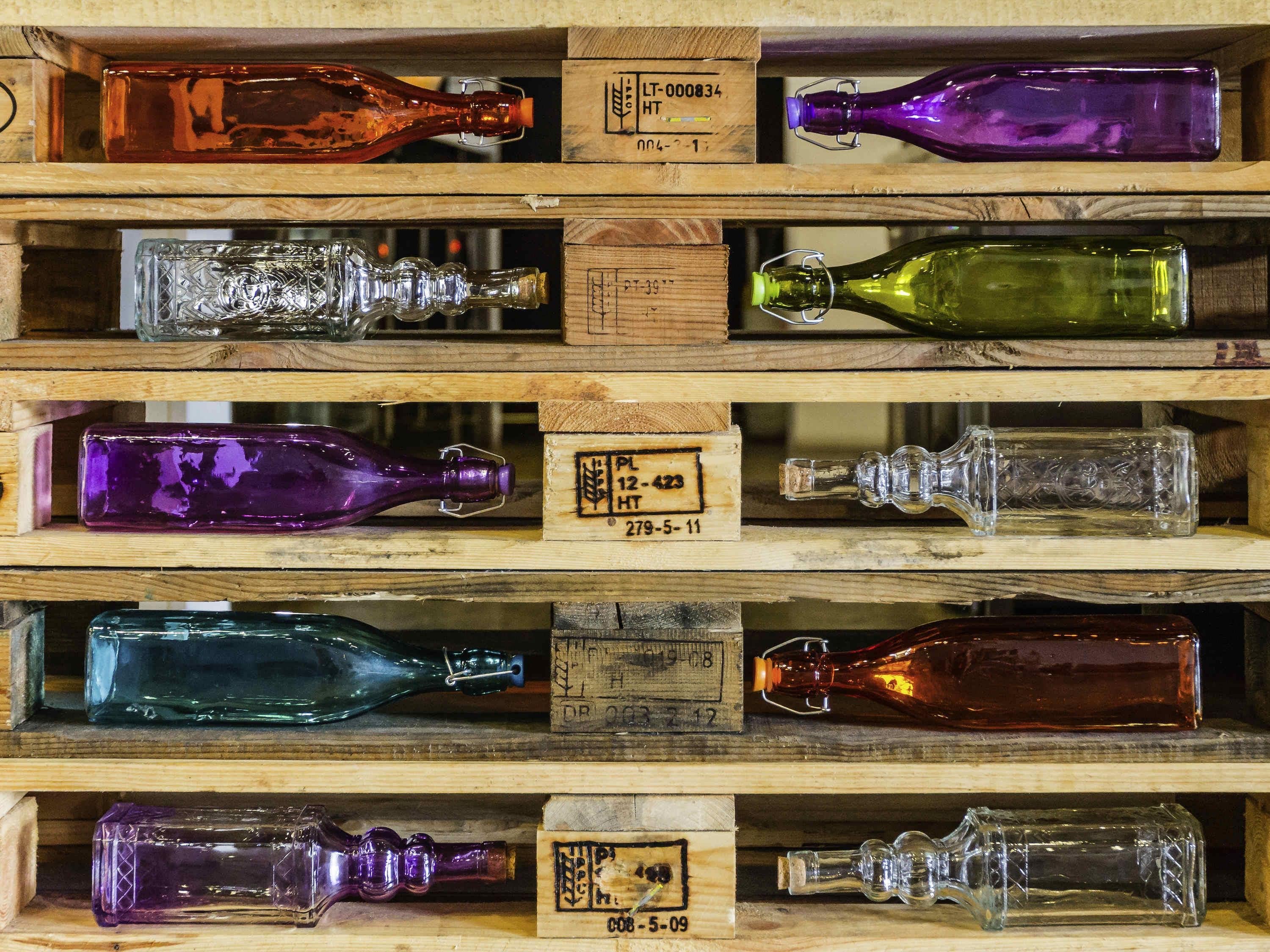A wooden display case containing various colored glass bottles, each with a label.