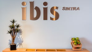A reception desk with a potted plant and a fruit crate. - ibis Lisboa Sintra (Sintra)