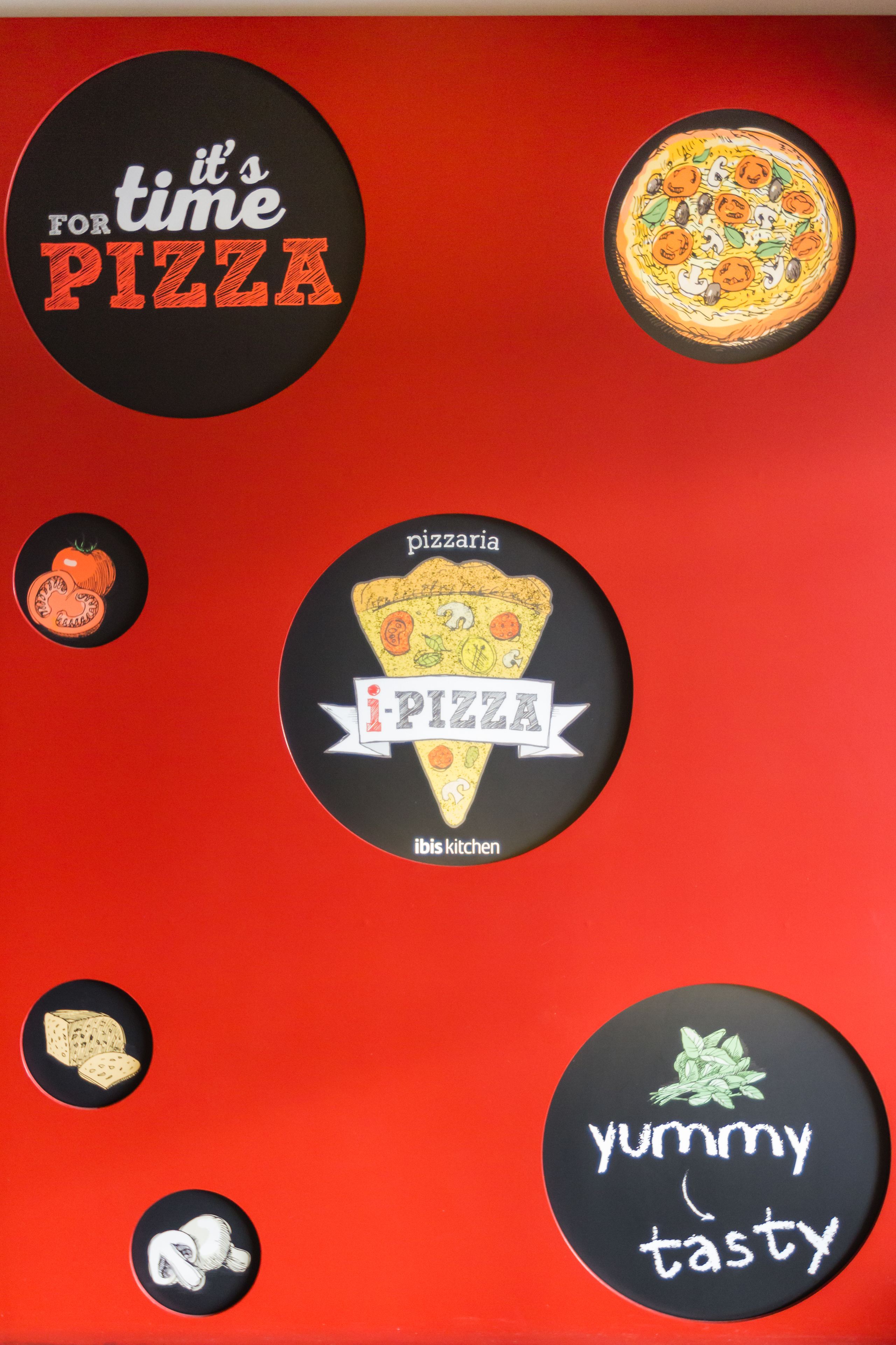 A wall with circular stickers featuring pizza-related designs and text.