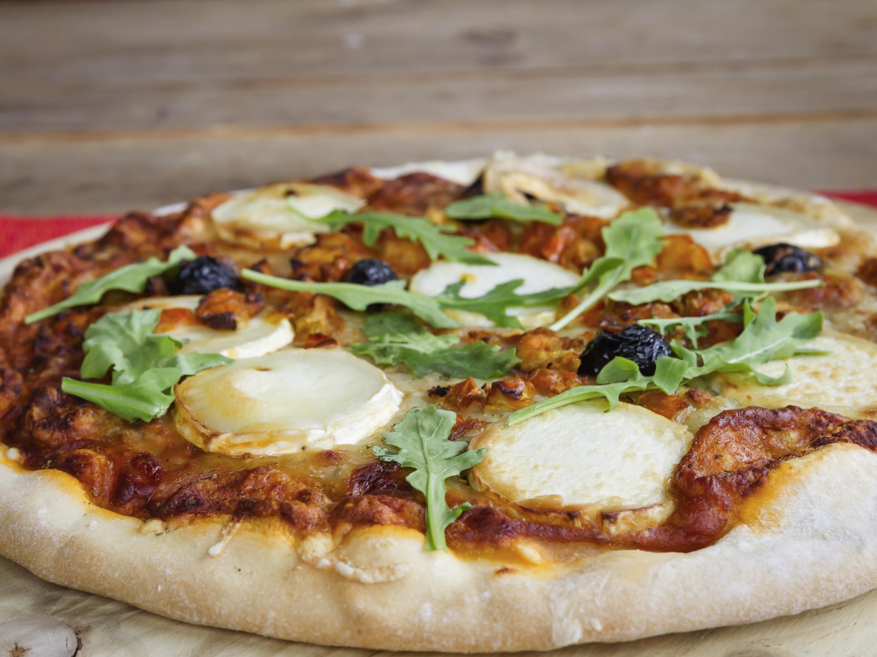 Une pizza garnie et une table en bois.