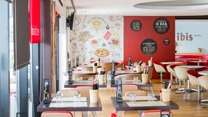 A restaurant interior with tables, chairs, and a menu stand. - ibis Lisboa Sintra (Sintra)
