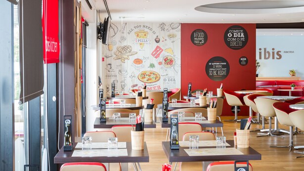 Interior de restaurante con mesas, sillas y un atril para el menú.