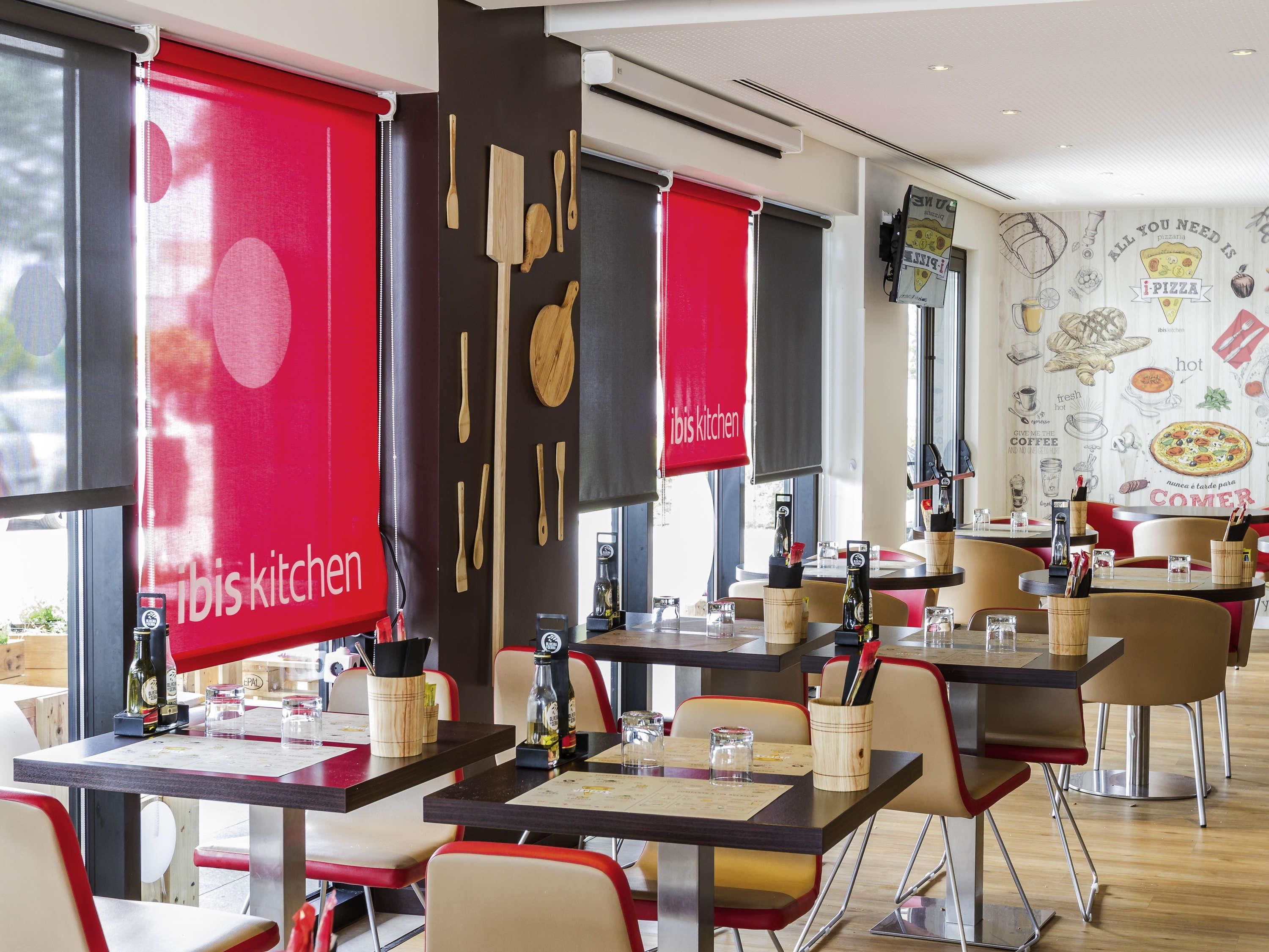 A restaurant interior with red and black decor, wooden utensils on the wall, and tables set for dining.