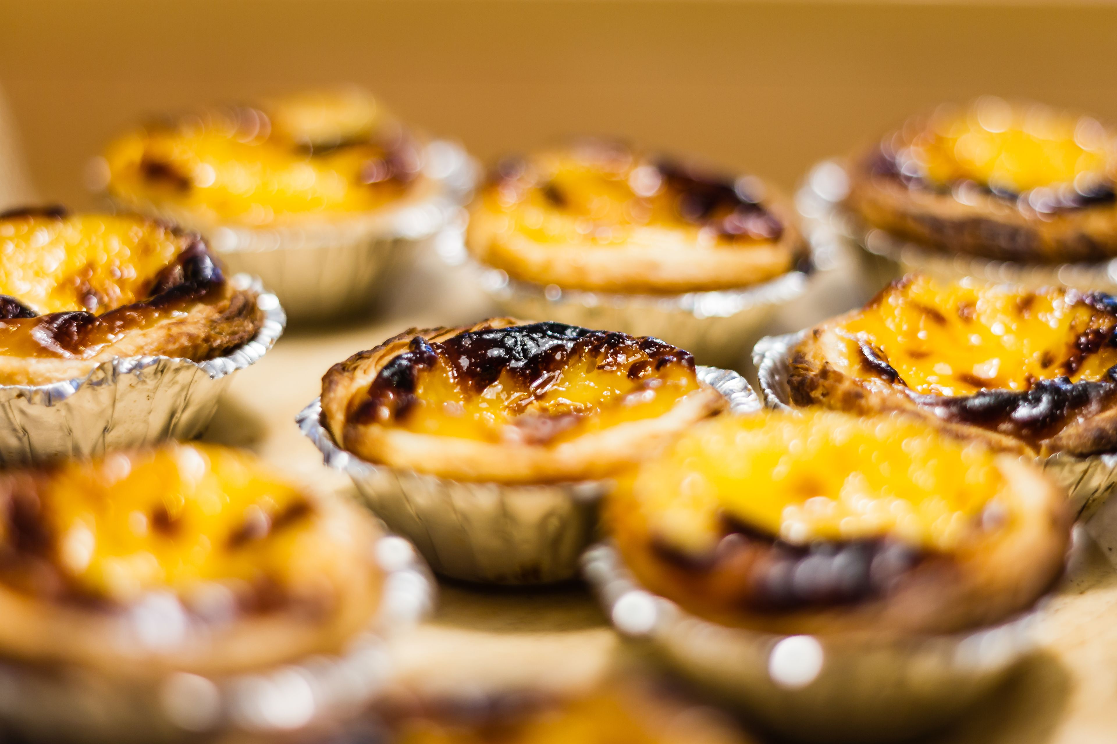 Primer pla de diverses pastes de nata portugueses amb una crosta daurada i una capa caramel·litzada brillant.