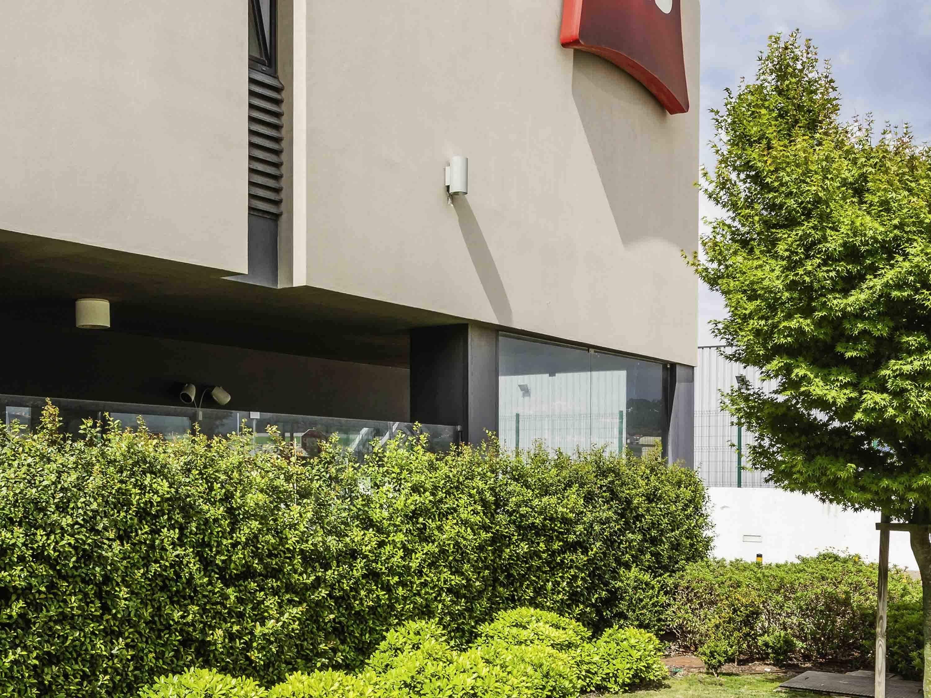 A modern building with a flat roof, large windows, and a red accent on the facade.