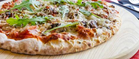 Une pizza servie sur une planche en bois, avec une serviette rouge placée en dessous.