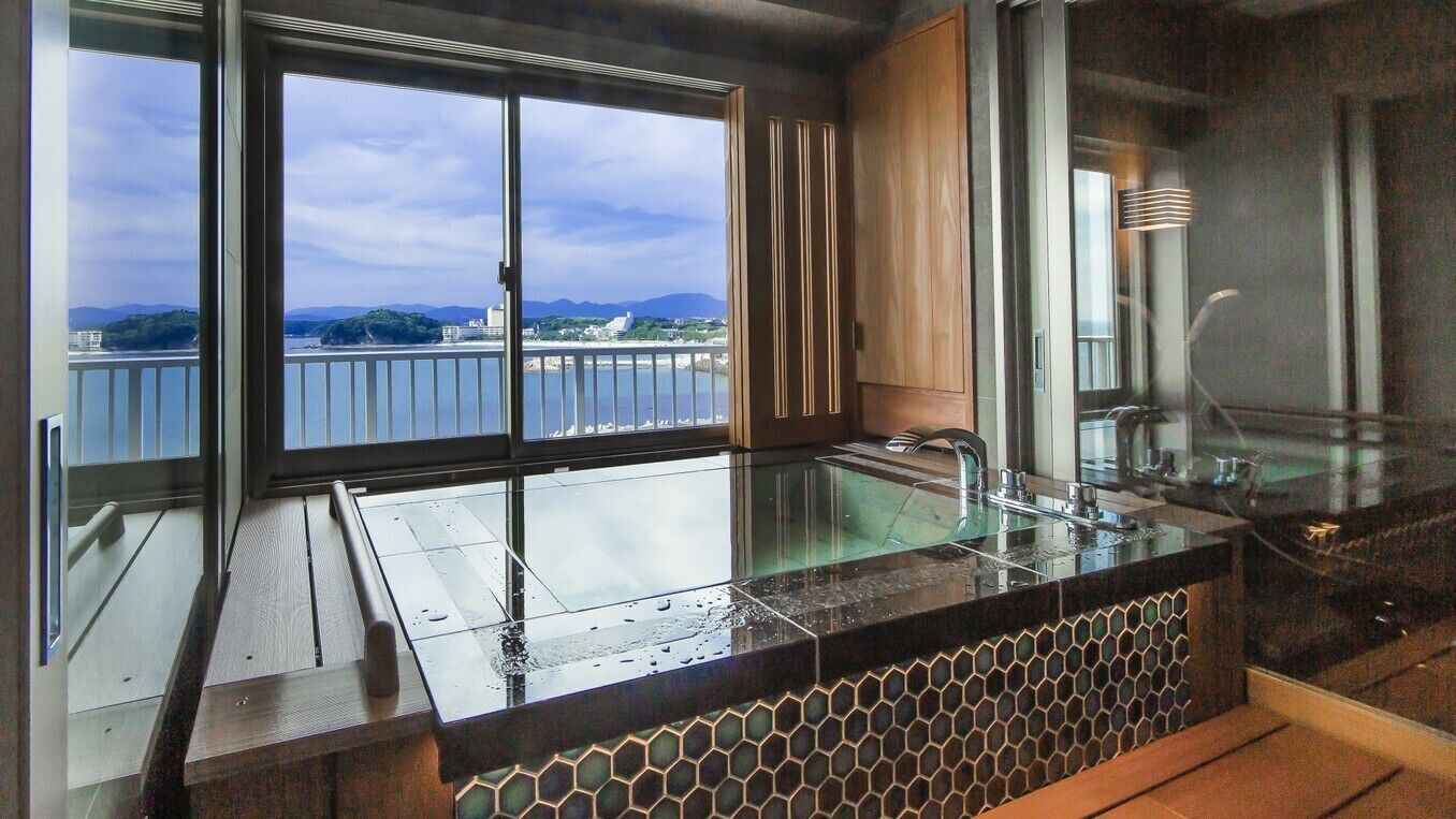 A modern kitchen with a large window, a glass sink, and a view of a body of water.