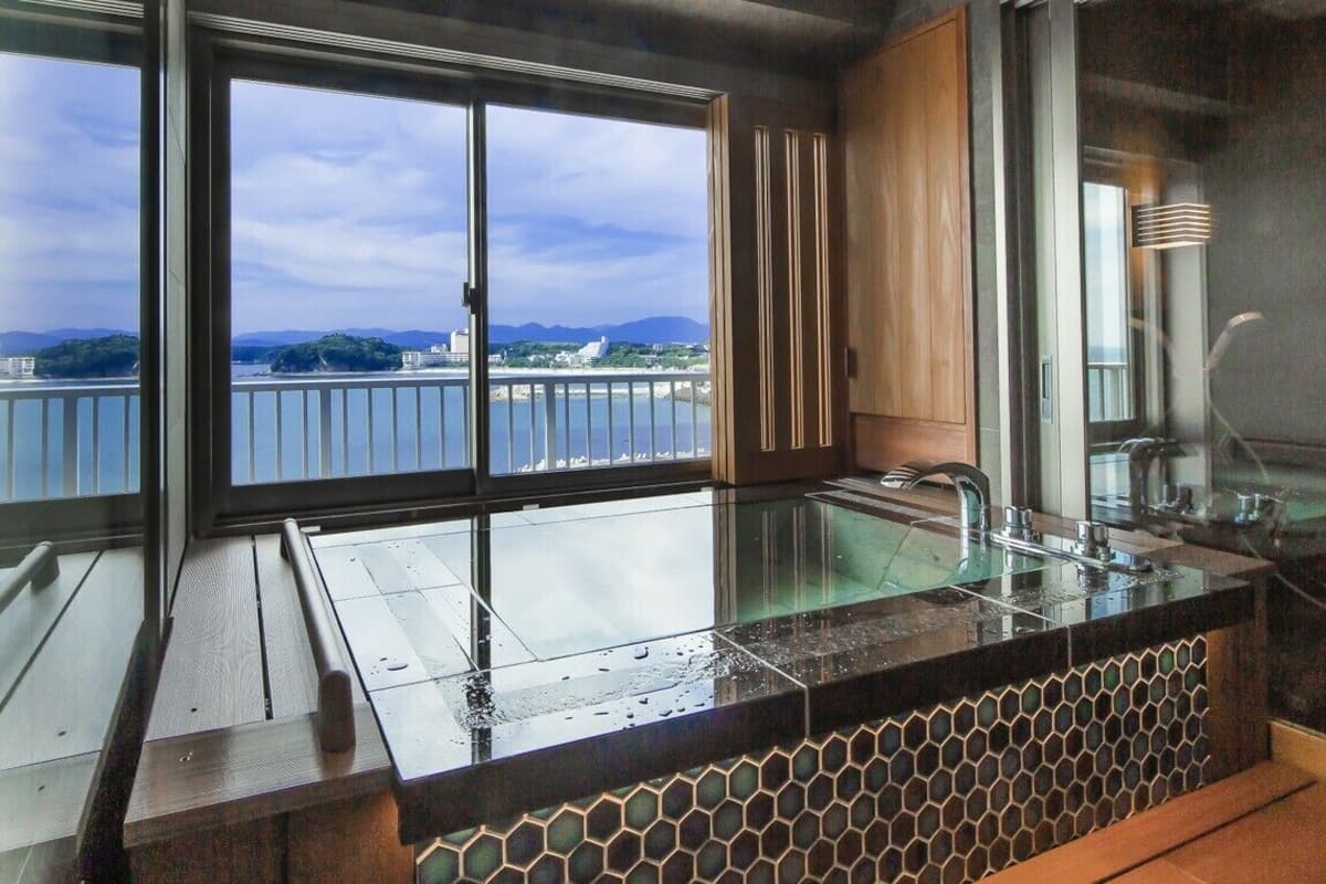 A modern kitchen with a large window, a glass sink, and a view of a body of water.